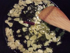 3.にんにくスライスと種を取り除いた唐辛子をオリーブオイルにて弱火で炒める。にんにくは焦がさないように注意。